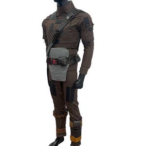 May include: A dark brown tactical costume set featuring a high-neck top, matching trousers, and a layered utility belt system. The ensemble includes a light grey abdominal plate, a diagonal shoulder strap with shell loops, and various pouches.