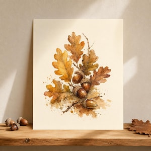 Könnte beinhalten: Ein Aquarellgemälde auf cremefarbenem Hintergrund mit einer Ansammlung brauner Eicheln und goldbrauner Eichenblätter. Das Kunstwerk zeigt detaillierte botanische Elemente mit Farbspritzern und weichen Schattierungen.