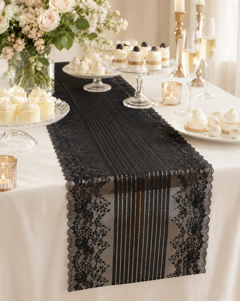 May include: A black lace table runner featuring a central panel of vertical stripes flanked by intricate floral lace borders with scalloped edges, draped over a white tablecloth and surrounded by various desserts and glassware.