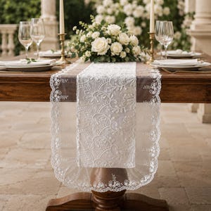 May include: A white lace table runner featuring intricate floral embroidery and scalloped edges with delicate bead accents. The runner is draped over a wooden table, showcasing a sheer mesh center panel and detailed needlework along the borders.