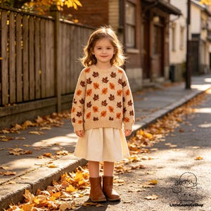 May include: A beige long-sleeved sweater featuring an all-over pattern of brown and orange autumn leaves, paired with a plain cream-colored skirt and brown leather ankle boots. The sweater has a ribbed crew neckline, cuffs, and hem.