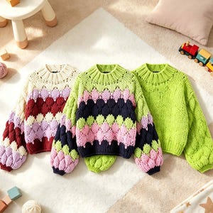 May include: Three long-sleeve knit sweaters with a chunky texture and ribbed crew necklines. The left sweater features cream, burgundy, and lavender. The center sweater has lime green, pink, and navy. The right sweater is solid lime green.