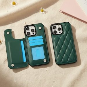 Könnte beinhalten: Zwei dunkelgrüne Handyhüllen für ein Smartphone mit Dreifachkamera. Eine Hülle ist geöffnet und zeigt ein Portemonnaie-Innenleben mit hellblauen Kartenfächern und einem Sichtfenster. Die andere Hülle ist geschlossen und hat ein Rautensteppmuster.
