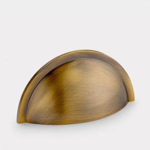 May include: A semi-circular cup pull handle with a brushed antique brass finish. The hardware features a smooth, rounded surface with a distinct curved edge, showcasing a metallic texture and warm golden-brown tones throughout the piece.