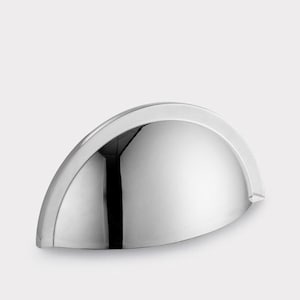 Op de afbeelding: Een komgreep van gepolijst chroom met een gladde, halfronde boogvorm. Het beslag heeft een reflecterende, spiegelachtige metalen afwerking met een gebogen voorzijde en platte bevestigingsranden aan beide zijden voor montage op meubels.