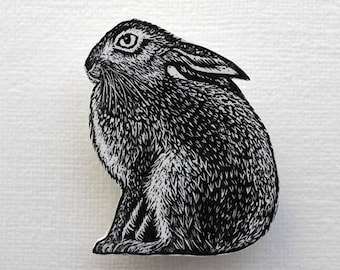 May include: Black and white illustration of a rabbit sitting on a white background.