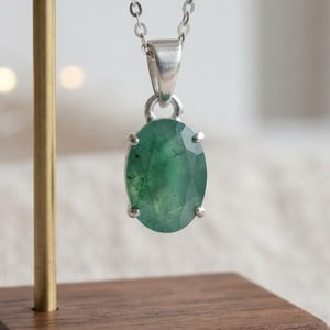 Natural Emerald Gemstone Necklace featuring a 10–15Ct oval-cut green emerald pendant suspended from a delicate silver-tone chain. The simple and elegant silhouette creates a timeless jewelry style that can transition easily from daytime to evening wear. Designed as May birthstone jewelry, this emerald pendant is suitable for birthdays, anniversaries, weddings, parties, dinners, office outfits, vacations, and everyday accessorizing for women who love classic gemstone jewelry.