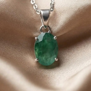 Beautiful Dainty Emerald Necklace featuring a 10–15Ct natural green gemstone in an elegant oval-cut design. The faceted emerald pendant catches the light while its natural inclusions and variations give the gemstone a unique appearance. This May birthstone necklace can be worn with everyday clothing, business outfits, evening dresses, wedding attire, and layered jewelry styles, making it an elegant gift for birthdays, anniversaries, Mother's Day, and special celebrations.