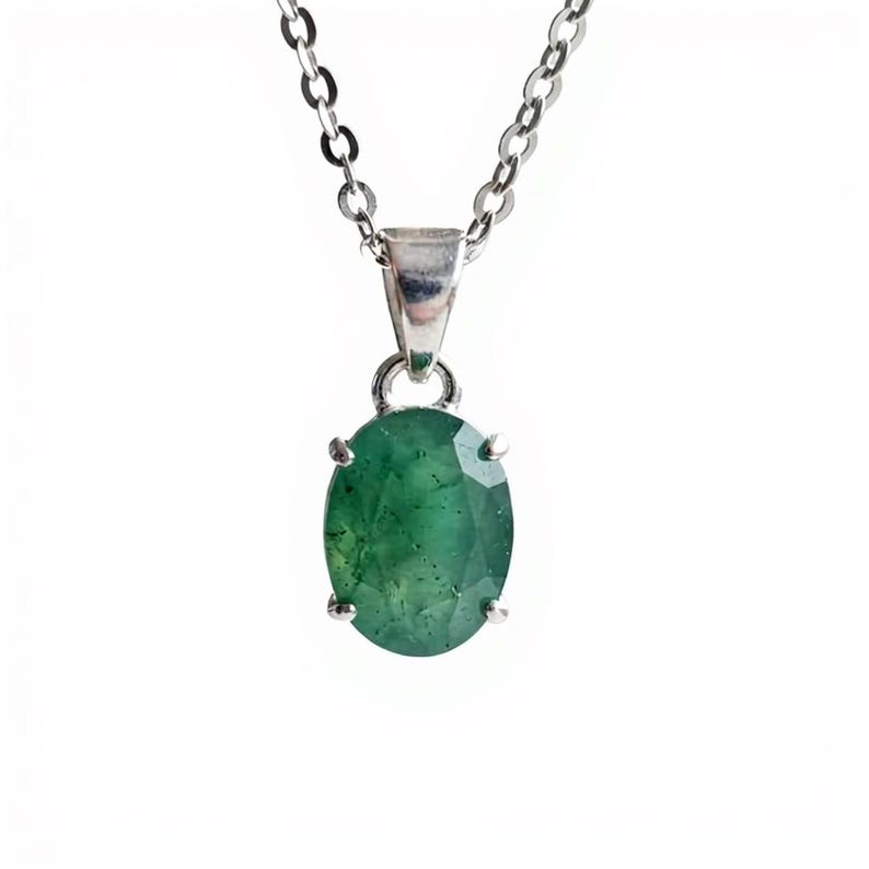 Natural Green Emerald Oval Pendant Necklace showcasing a 10–15Ct gemstone with a sophisticated faceted oval shape and distinctive natural characteristics. The dainty necklace design keeps the emerald as the center of attention while the delicate silver-tone chain adds a refined finish. Perfect as May birthstone jewelry for birthdays, Mother's Day, anniversaries, weddings, dinners, parties, vacations, and everyday styling.