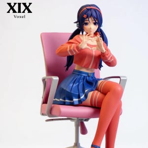 May include: A collectible anime-style figurine of a character with long dark blue hair, wearing a coral-colored cropped long-sleeve top and a pleated blue skirt, sitting on a pink office chair while forming a heart shape with their hands.
