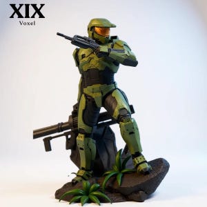 May include: A Master Chief action figure in olive green armor with a gold visor, holding a black assault rifle. The figure stands on a dark rock base with green foliage, featuring a large black weapon mounted behind it. Text XIX Voxel is visible.