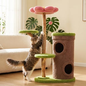 May include: A cat tree featuring a brown textured trunk-shaped base with two circular openings, a central wooden post with a sisal rope section, two green circular platforms, and a top platform shaped like a pink flower with a hanging ball toy.