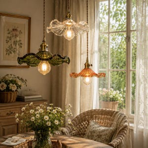 May include: Three pendant lights with ruffled glass shades in clear, green, and amber colors. Each lamp features a brass-toned metal fixture and a warm glowing light bulb suspended by a twisted cord, creating a decorative lighting arrangement.