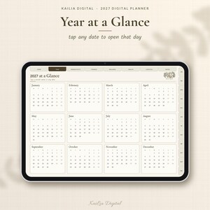 K&ouml;nnte beinhalten: Ein digitales Tablet mit einer Kalenderseite f&uuml;r 2027 mit dem Titel Year at a Glance. Die Benutzeroberfl&auml;che zeigt zw&ouml;lf Monatsraster von Januar bis Dezember, Navigationsregisterkarten und den Text Kailia Digital 2027 Digital Planner.