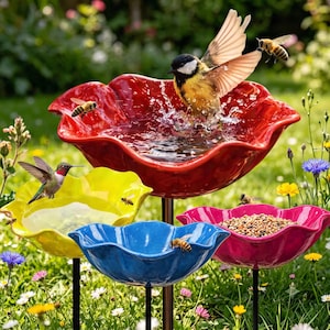 Peut inclure: Un ensemble de bain d'oiseaux et de mangeoire à plusieurs niveaux composé de quatre bols en forme de fleur rouge, jaune, bleu et magenta. Le bol rouge contient de l'eau avec un oiseau, le jaune de l'eau, le bleu est vide et le magenta des graines.