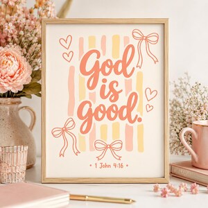 Puede incluir: Una lámina decorativa enmarcada con el texto God is good en una fuente cursiva color coral, centrada sobre rayas verticales en amarillo pálido y melocotón. El diseño incluye lazos y corazones dibujados a mano, con la cita 1 John 4:16 abajo.