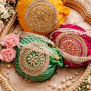 Peut inclure: Trois pochettes rondes à cordon de serrage en jaune, vert et magenta, chacune dotée d'un médaillon central circulaire doré avec des broderies complexes et des accents métalliques. Les pochettes sont ornées de perles blanches en guise de anses.