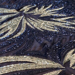 May include: Black and silver sequined fabric with a geometric pattern. The sequins are arranged in a swirling design, creating a shimmering effect.