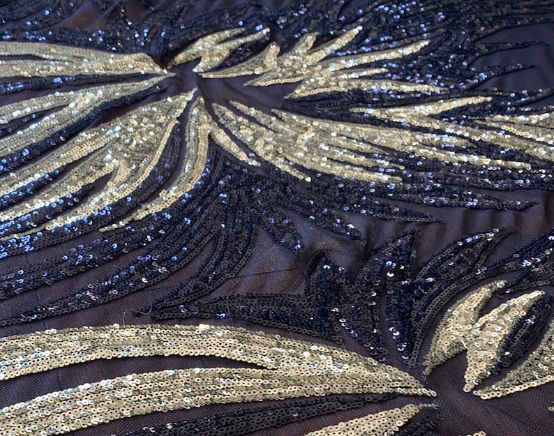 May include: Black and silver sequined fabric with a geometric pattern. The sequins are arranged in a swirling design, creating a shimmering effect.