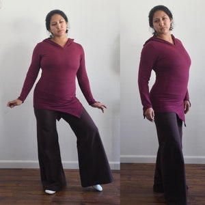 Puede incluir: Una sudadera con capucha de color granate con manga larga y dobladillo drapeado. La sudadera se combina con pantalones marrones de pierna ancha.