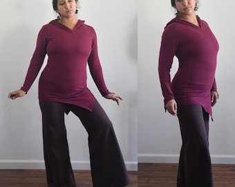 May include: A maroon hooded top with a long sleeve and a draped hemline. The top is paired with brown wide-leg pants.