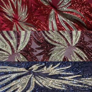 May include: Three fabric swatches with a sequined floral pattern. The top swatch is red with gold sequins, the middle swatch is burgundy with silver sequins, and the bottom swatch is navy blue with silver sequins.