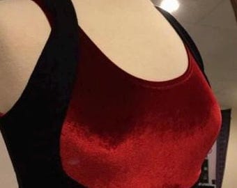 May include: A black and red velvet crop top displayed on a mannequin. The top features a scoop neckline and a contrasting color block design. The bodice is a deep red, while the straps and back are black.