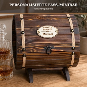 Könnte beinhalten: Eine dunkelbraune Minibar in Fassform aus Holz mit zwei beigen Seilbändern und messingfarbenen Nieten. Ein ovales Schild auf der Vorderseite trägt die Aufschrift "PRIVATE RESERVE Michael" über einem schwarzen Metallringgriff.