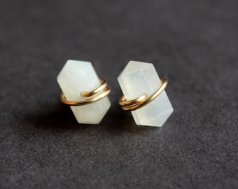 Puede incluir: Un par de pendientes con cristales de piedras preciosas blancas envueltos en alambre dorado.