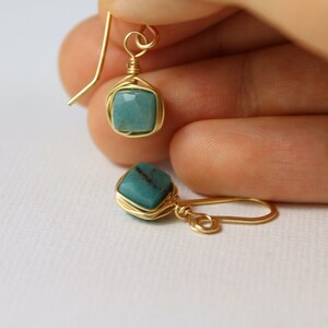 May include: A pair of gold wire wrapped earrings with turquoise green gemstone accents.