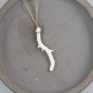 Puede incluir: Un delicado collar con un colgante de rama de coral blanco y una cadena de oro. La rama de coral tiene una forma natural y una textura &uacute;nica.