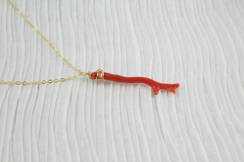 Puede incluir: Un collar de cadena de oro con un colgante de rama de coral rojo. La rama de coral est&aacute; envuelta en alambre de oro en la parte superior.