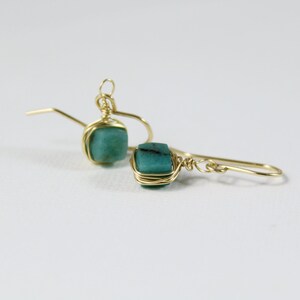 May include: A pair of gold wire wrapped earrings with turquoise green stones.