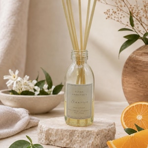 May include: A clear glass reed diffuser bottle containing a light yellow liquid with five beige reeds. The label reads ELVAN AROMATICS, Sunrise, REED DIFFUSER, Sweet Orange, Bergamot, May Chang, 100ml | Pure Essential Oils | Hand Blended.
