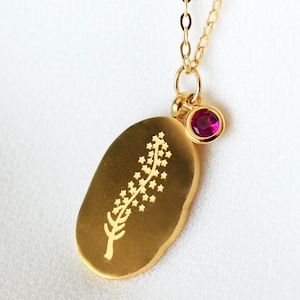 以下が含まれることがあります： スタイリッシュな花柄のデザインと小さなピンクの宝石のアクセントが施されたゴールドネックレスのペンダント