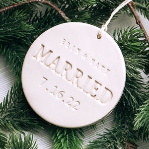 White round ceramic ornament with the text "Britt & Matt Married 7.16.22" embossed on the front.