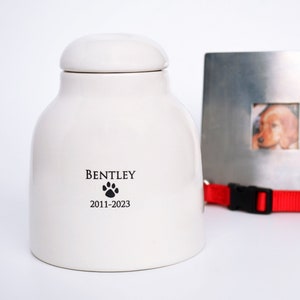 white ceramic pet urn with name and date with paw print