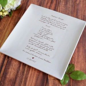 May include: A white ceramic serving dish with a handwritten recipe for meat pie. The recipe includes ingredients and instructions for making the pie. The dish is decorated with the words "25 YEARS" and a heart.
