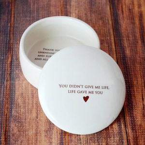 May include: White ceramic trinket box with a lid. The lid has the text "You didn't give me life, life gave me you" with a small red heart.