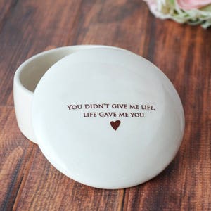 May include: White ceramic trinket box with a lid. The lid has the text "You didn't give me life, life gave me you" and a small heart.