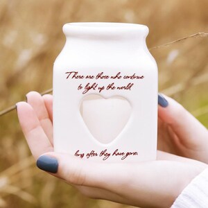 May include: White ceramic jar with a heart-shaped cutout and the text "There are those who continue to light up the world long after they have gone."