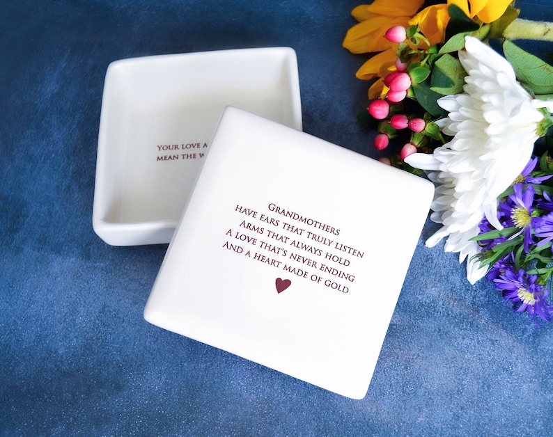 White ceramic box with a lid. The box has a heart and the text "Grandmothers have ears that truly listen, arms that always hold, a love that's never ending and a heart made of gold."