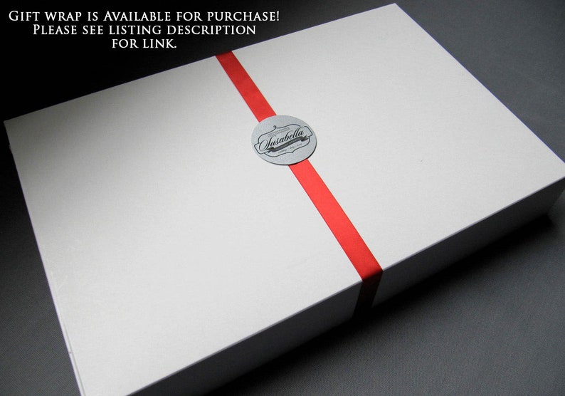 May include: A white gift box with a red ribbon and a silver sticker that says "Ansabella".