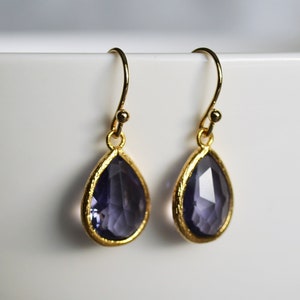 K&ouml;nnte beinhalten: Ein Paar goldene Ohrringe mit tropfenf&ouml;rmigen Amethyststeinen.