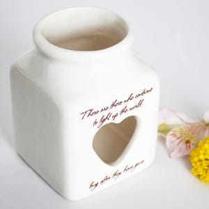 May include: White ceramic candle holder with a heart-shaped cutout and the quote "There are those who continue to light up the world, long after they have gone."