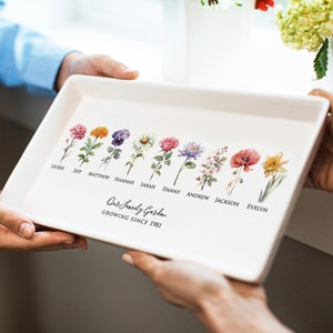 May include: A white ceramic serving tray featuring a floral design and the text "Our Family Garden Growing Since 1981". Each flower is labelled with a name, such as "Jeff", "Matthew", "Hannah", "Sarah", "Danny", "Andrew", "Jackson", and "Evelyn".