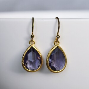 K&ouml;nnte beinhalten: Ein Paar goldene Ohrh&auml;nger mit tropfenf&ouml;rmigen Amethyststeinen.