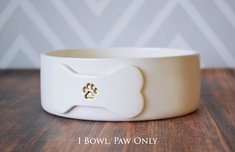 Image of the 1 bowl, paw only option. One bowl is shown with a bone shaped tile on the front. The tile is stamped with a paw print image and painted in metallic gold.