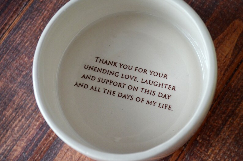 May include: White ceramic bowl with a brown inscription that reads "THANK YOU FOR YOUR UNENDING LOVE, LAUGHTER AND SUPPORT ON THIS DAY AND ALL THE DAYS OF MY LIFE."