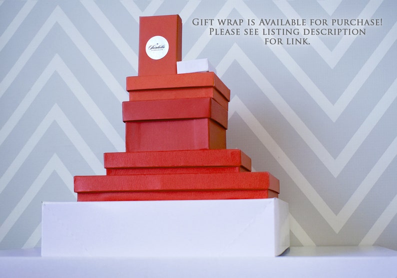 Informational image with directions on adding a gift box.  Shows a group of gift boxes of various sizes. Each is solid red or white with a metallic silver Susabella seal. Gift wrap is available for purchase. Please see listing description for link.